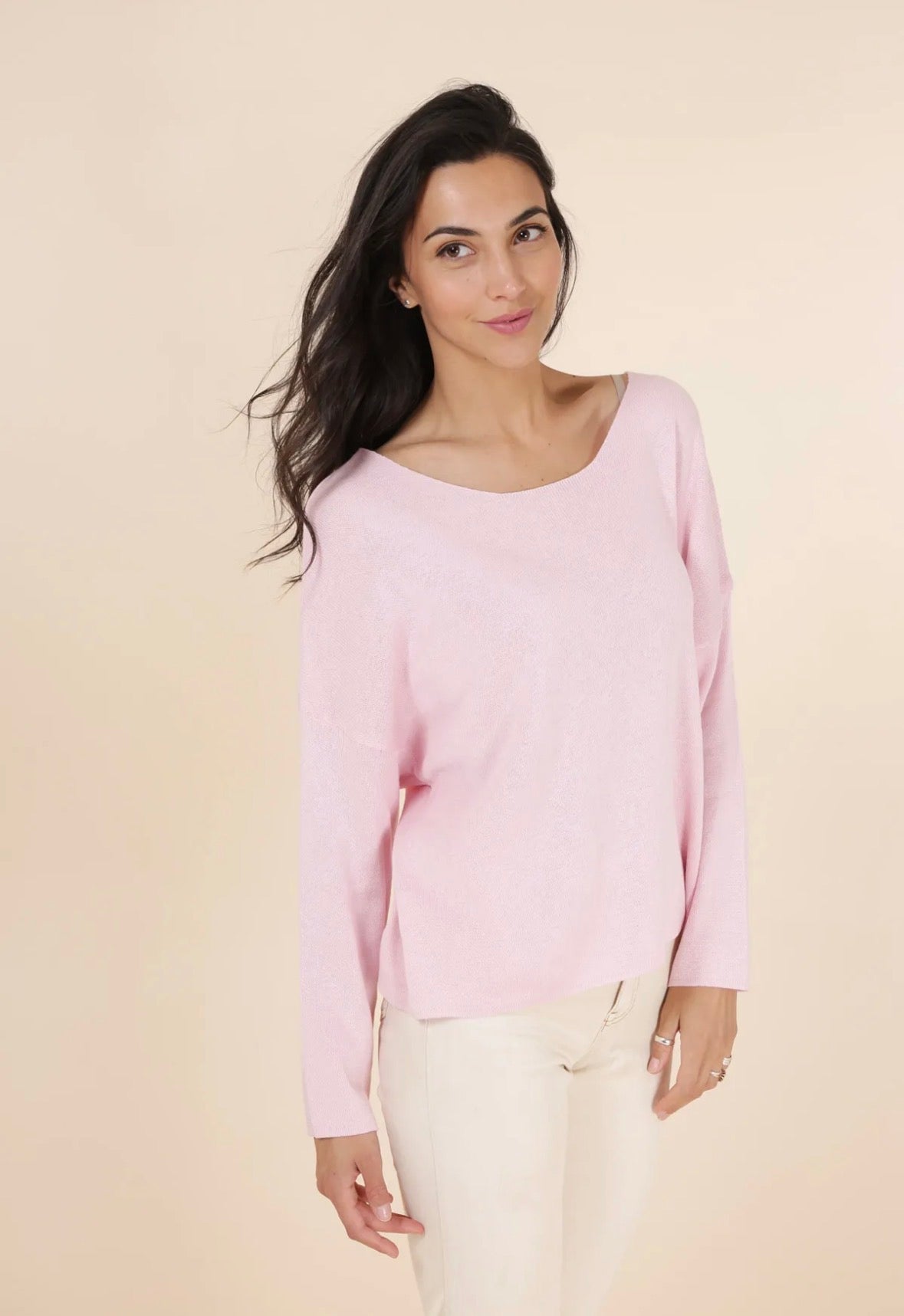 Woman wearing a light pink sweater against a beige background