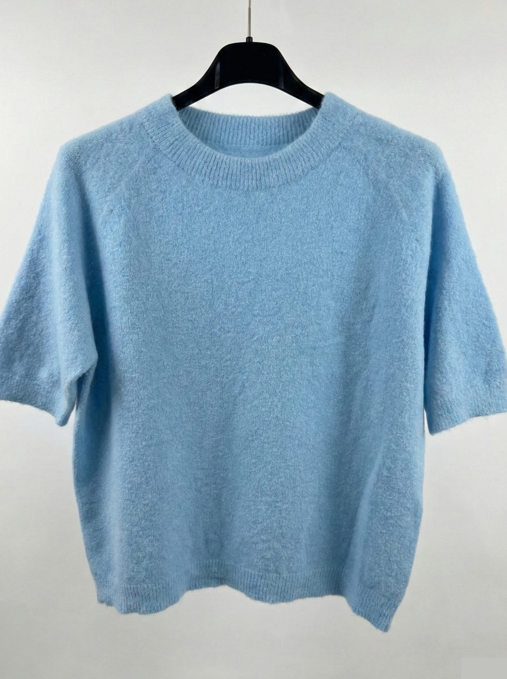 Light blue sweater on a hanger against a white background