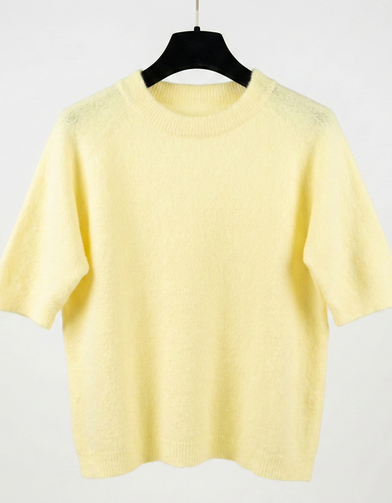 Yellow sweater on a hanger against a white background