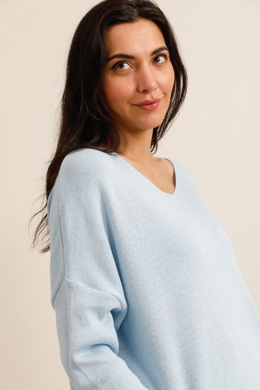 Woman wearing a light blue sweater against a beige background