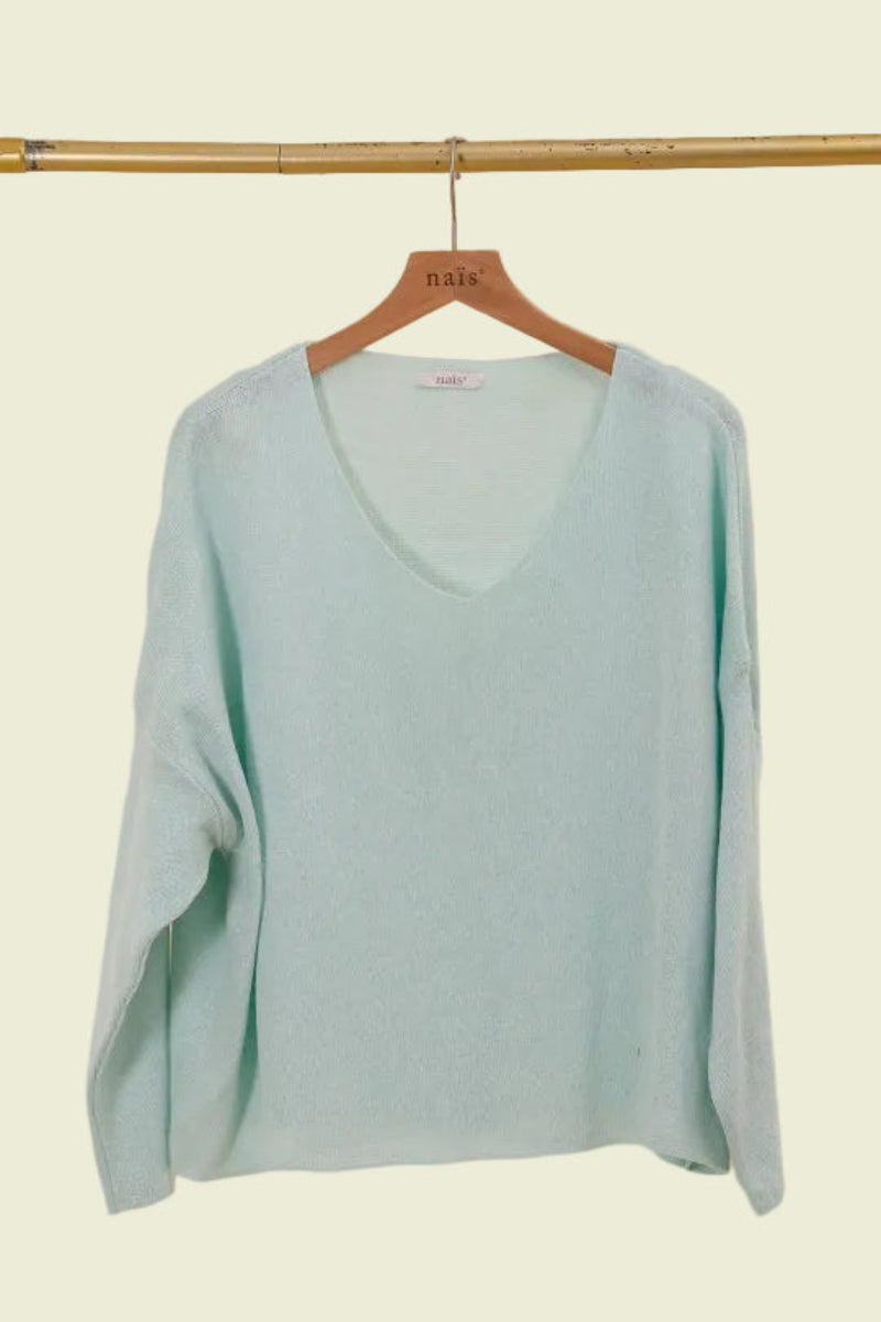 Light blue sweater on a wooden hanger against a beige background