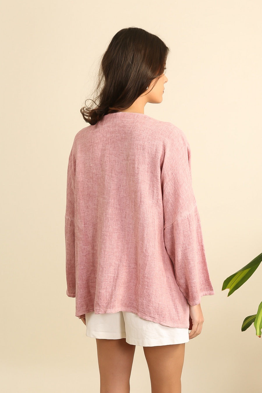 Woman wearing a pink linen jacket on a beige background