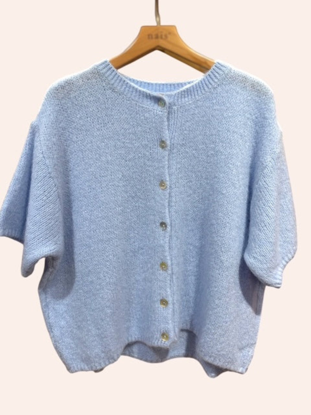 Light blue knitted cardigan on a wooden hanger against a plain background