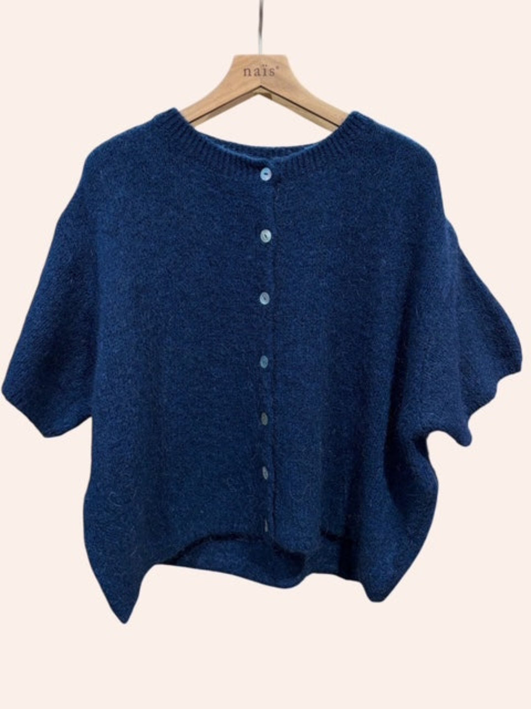 Blue cardigan on a hanger against a beige background