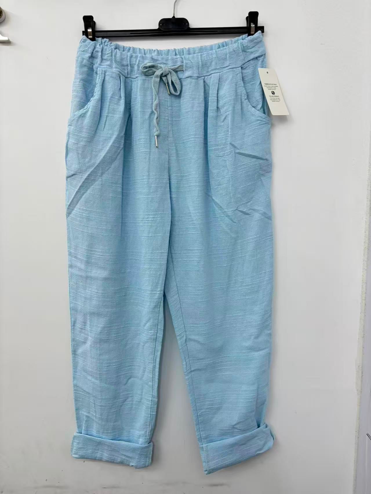 Light blue pants with a drawstring on a hanger against a white background