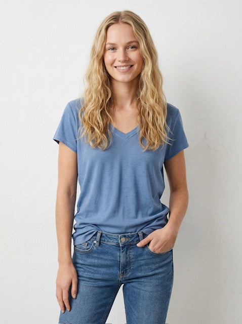 Woman wearing a blue t-shirt and jeans against a plain background