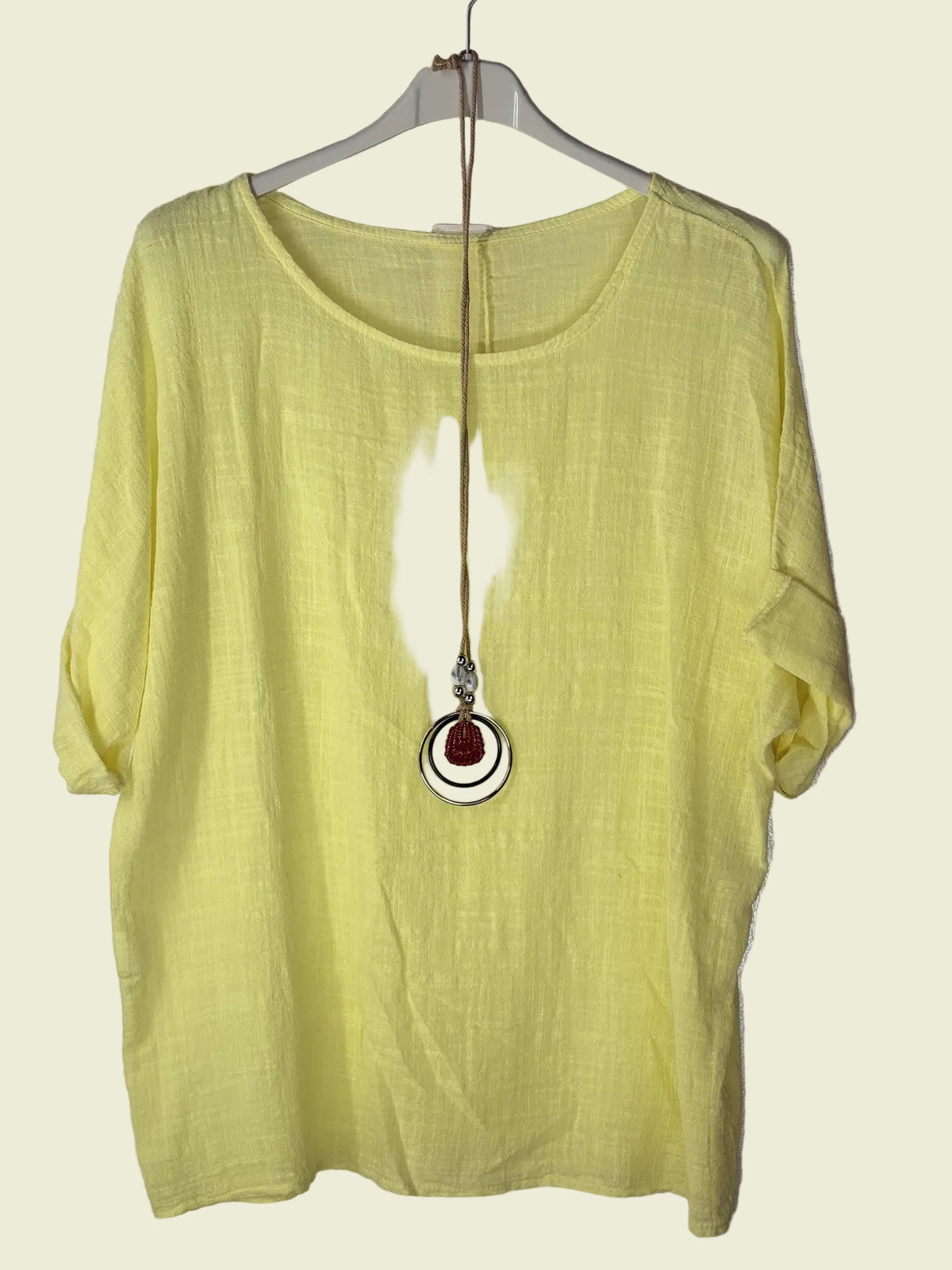 Yellow shirt on a hanger with a necklace