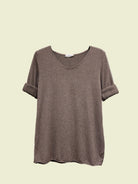Brown t-shirt on a hanger against a neutral background