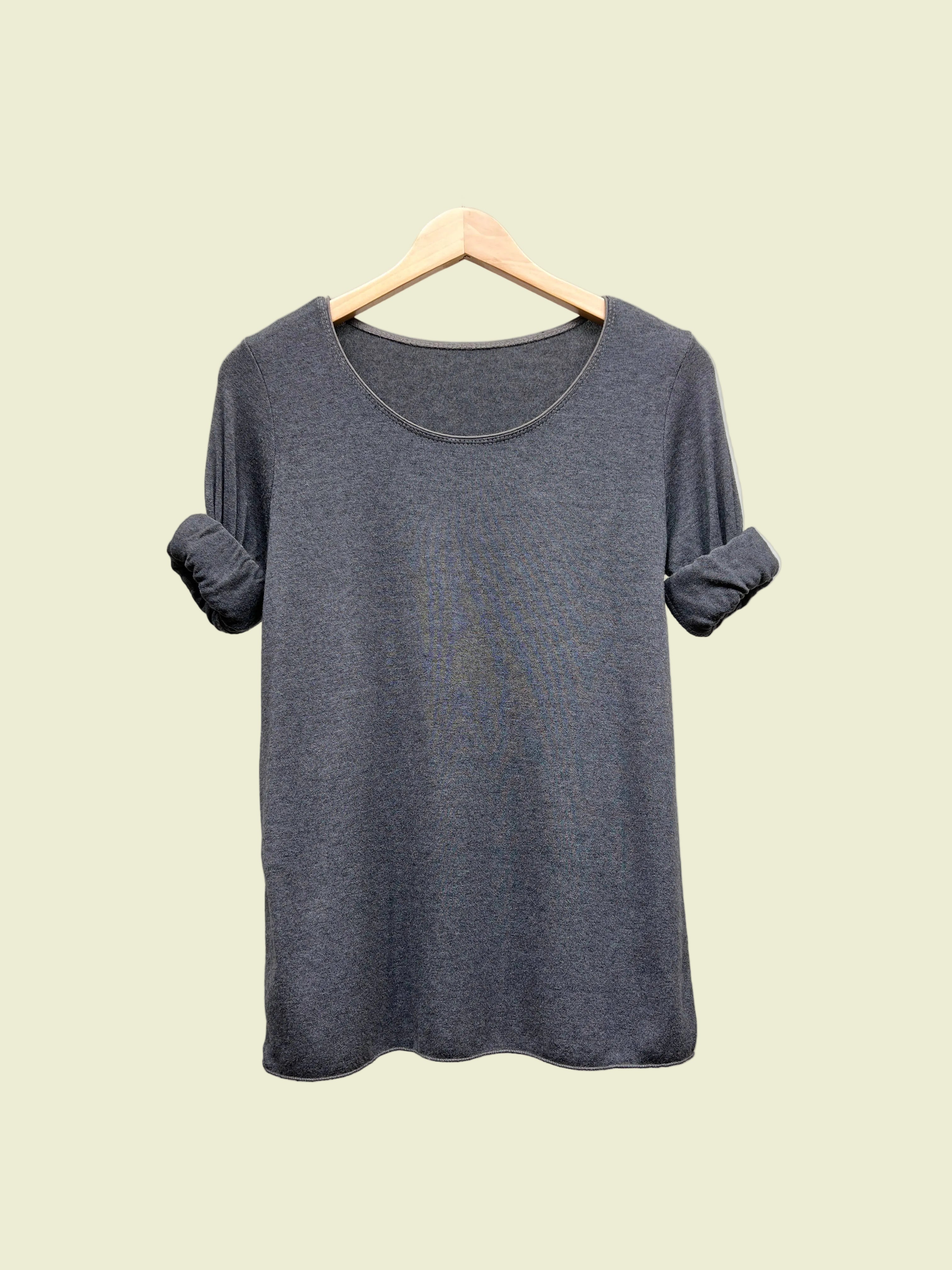 Grey top on a hanger against a plain background