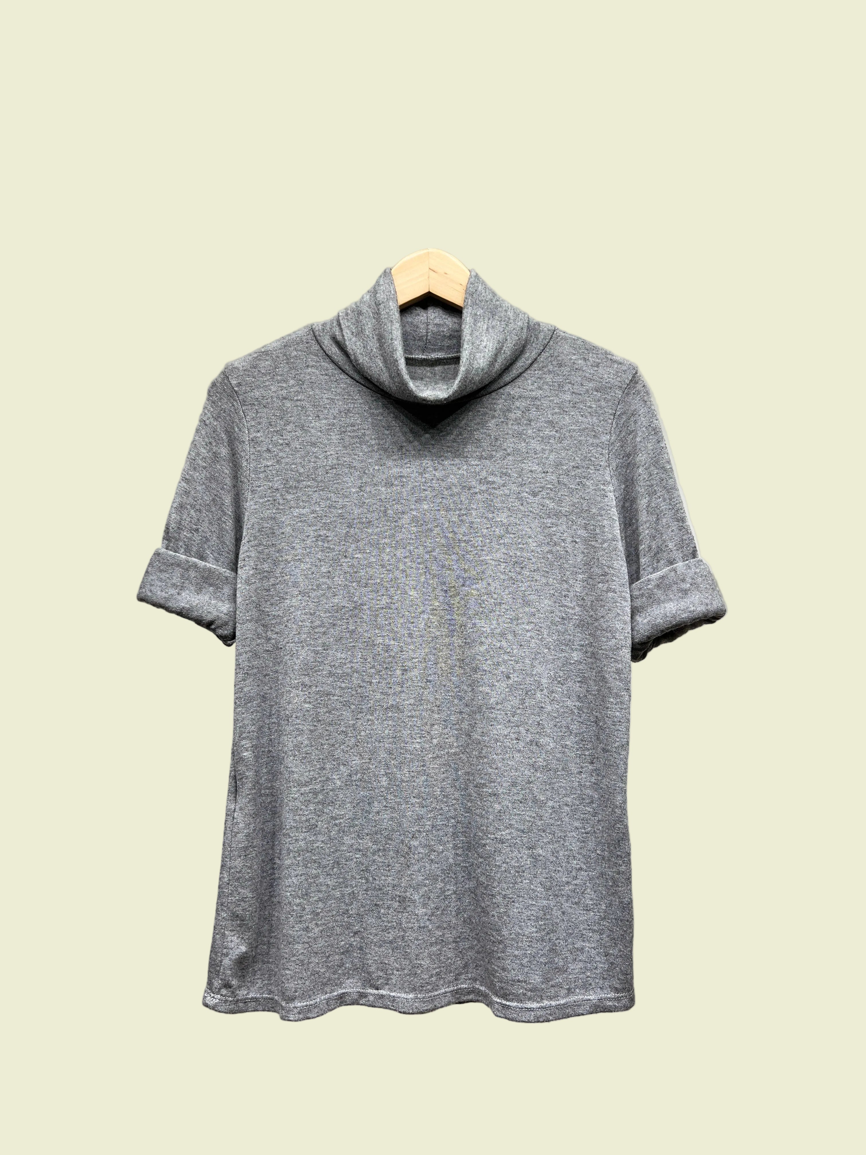 Grey turtleneck top on a hanger against a neutral background