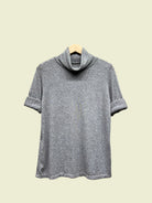 Grey turtleneck top on a hanger against a neutral background