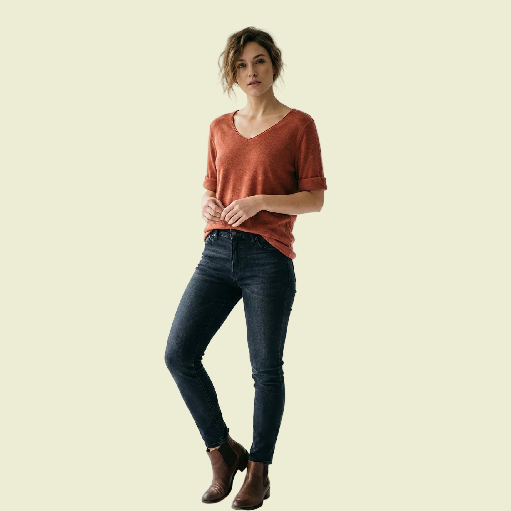 Woman wearing a rust-colored shirt and dark jeans on a white background