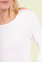 Close-up of a person wearing a white long-sleeve shirt on a plain background