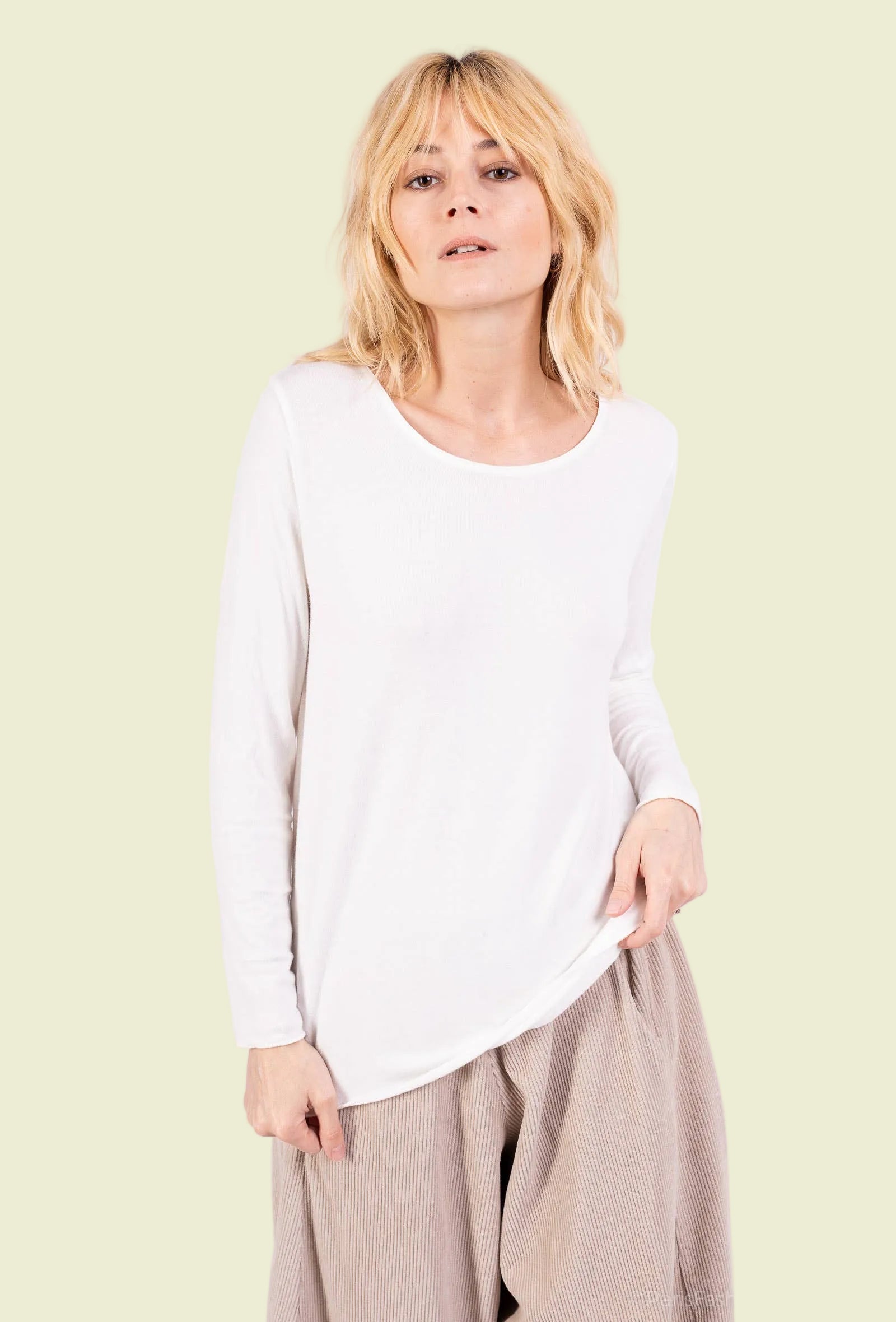 Woman wearing a white top and beige pants on a white background