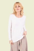 Woman wearing a white top and beige pants on a white background