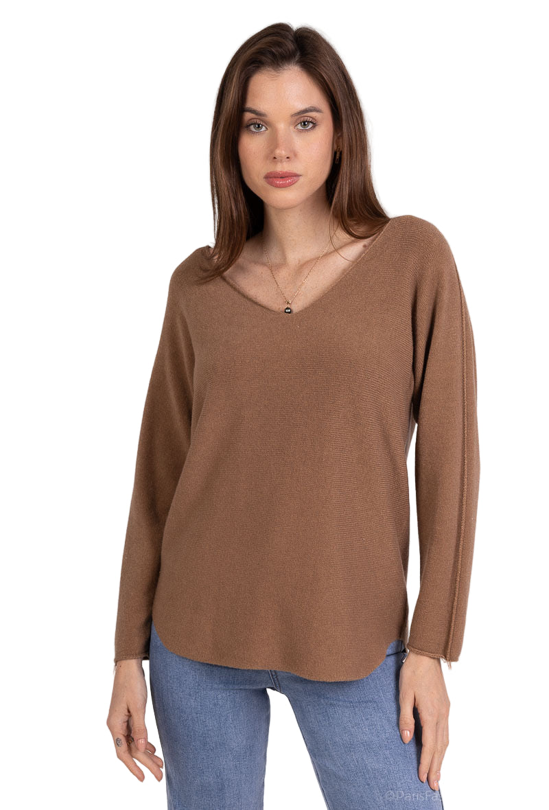 Woman wearing a brown long-sleeve top and blue jeans on a plain background