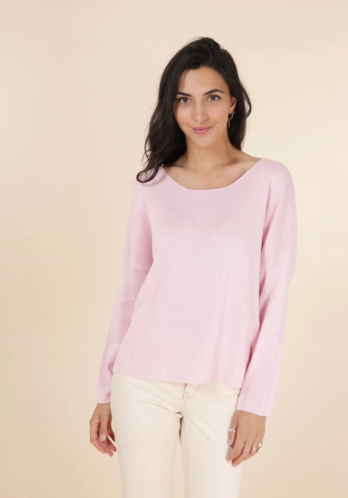 Woman wearing a light pink sweater against a beige background