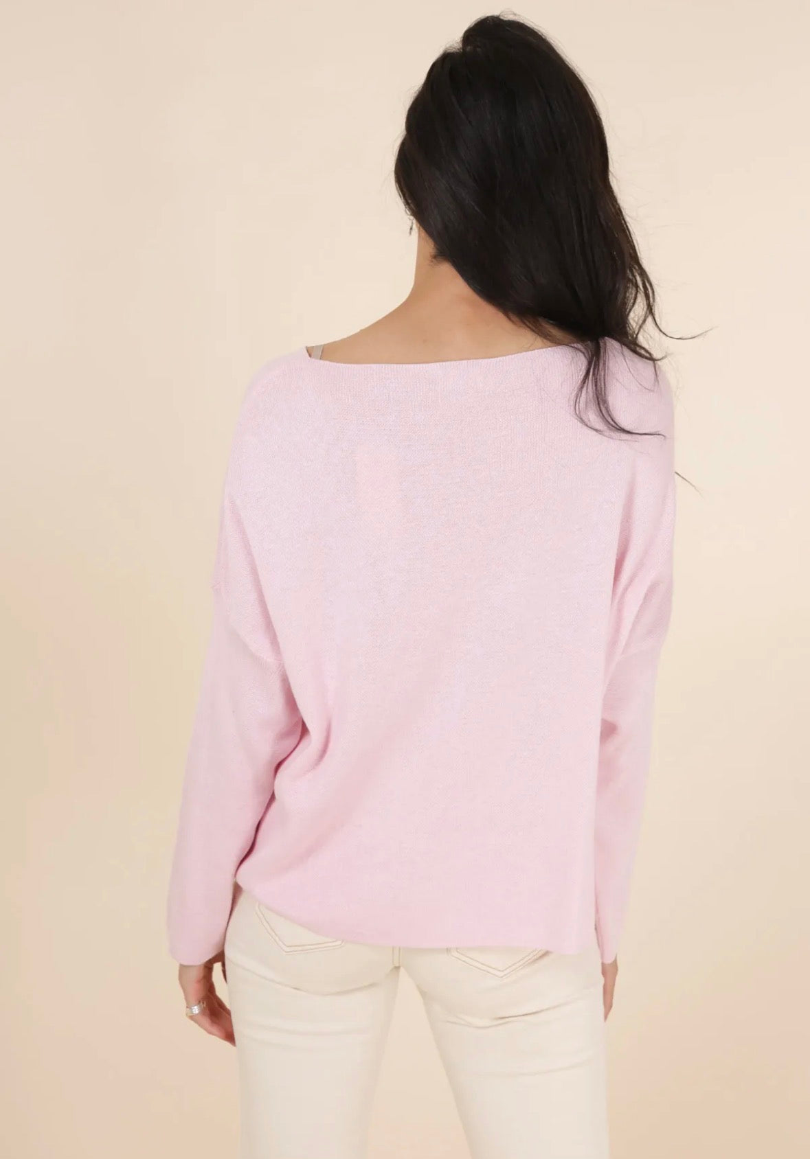 Person wearing a light pink sweater against a beige background