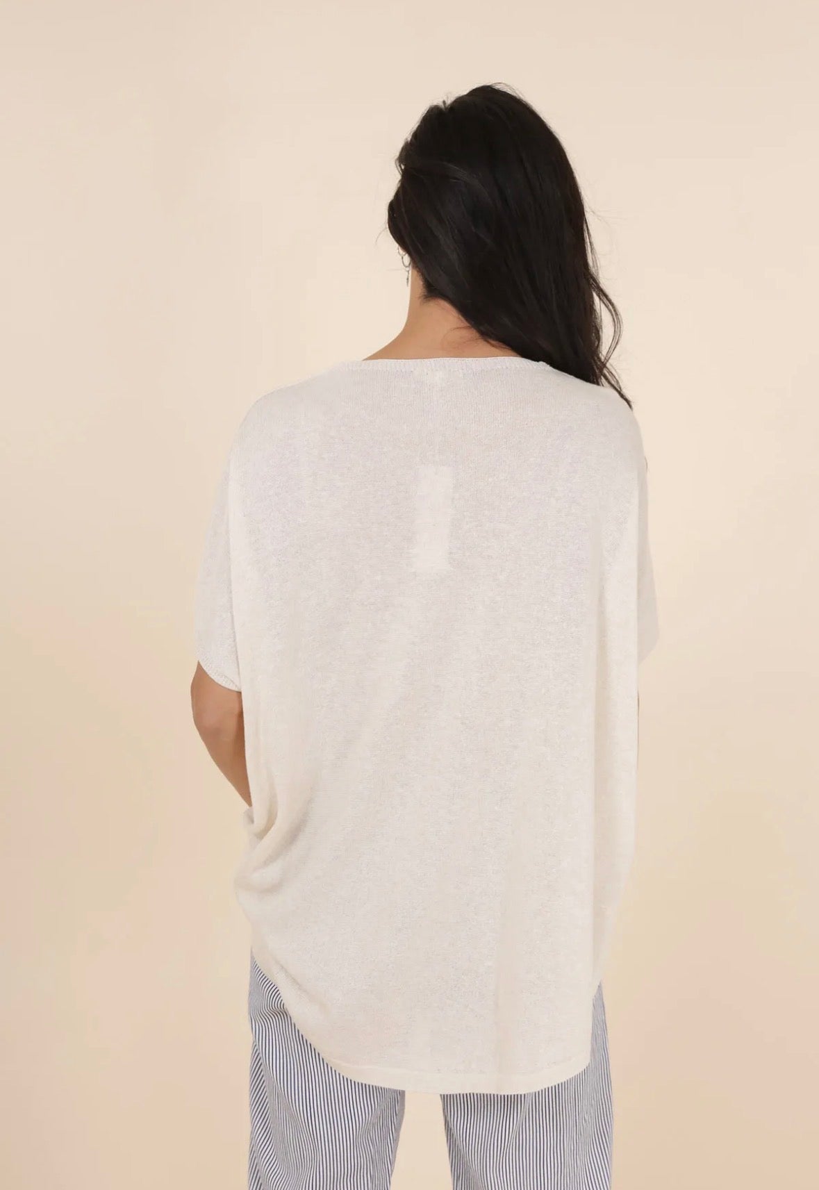 Person wearing a white sweater against a beige background