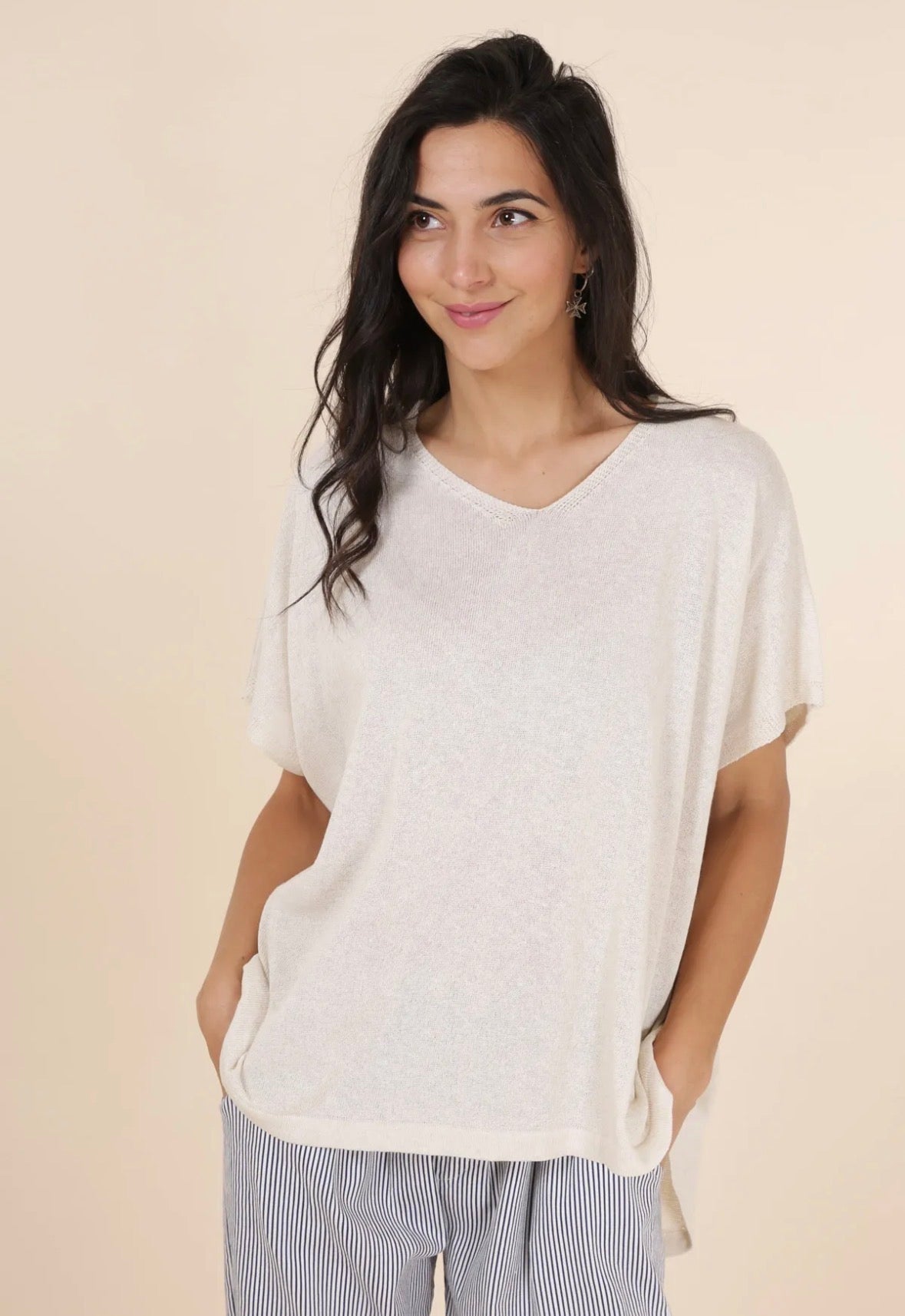 Woman wearing a loose-fitting white top with a neutral background
