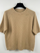 Beige sweater on a black hanger against a white background