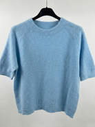 Light blue sweater on a hanger against a white background