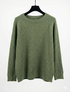 Green sweater on a hanger against a white background