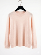 Pink sweater on a hanger against a white background