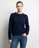 Person wearing a navy sweater and blue jeans against a plain background