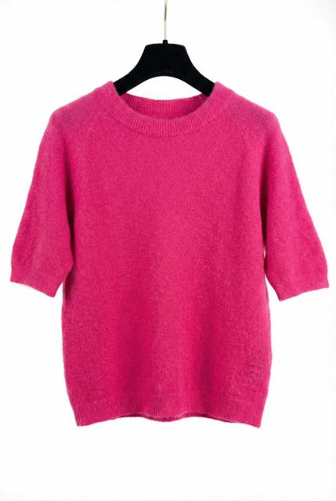 Pink sweater on a black hanger against a white background