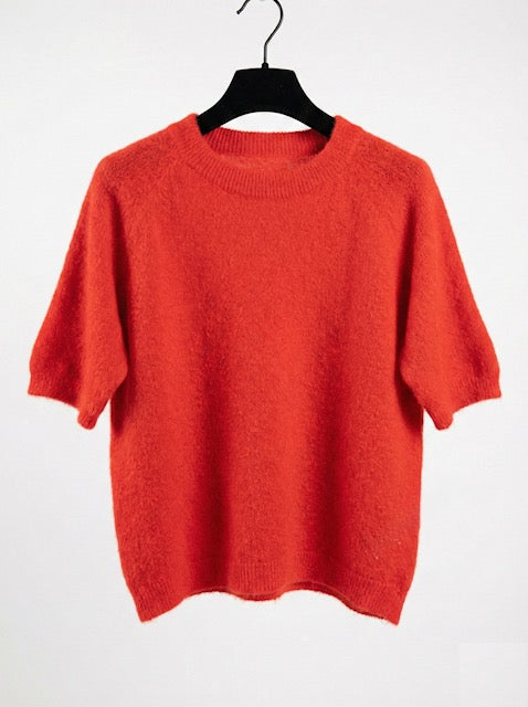 Orange sweater on a hanger against a white background