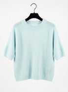 Light blue sweater on a hanger against a white background