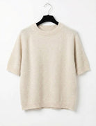 Beige sweater on a hanger against a white background