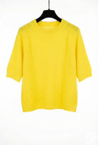 Yellow sweater on a black hanger against a white background