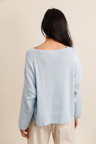 Woman wearing a light blue sweater against a beige background