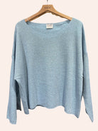 Light blue sweater on a hanger with 'nais' label against a white background