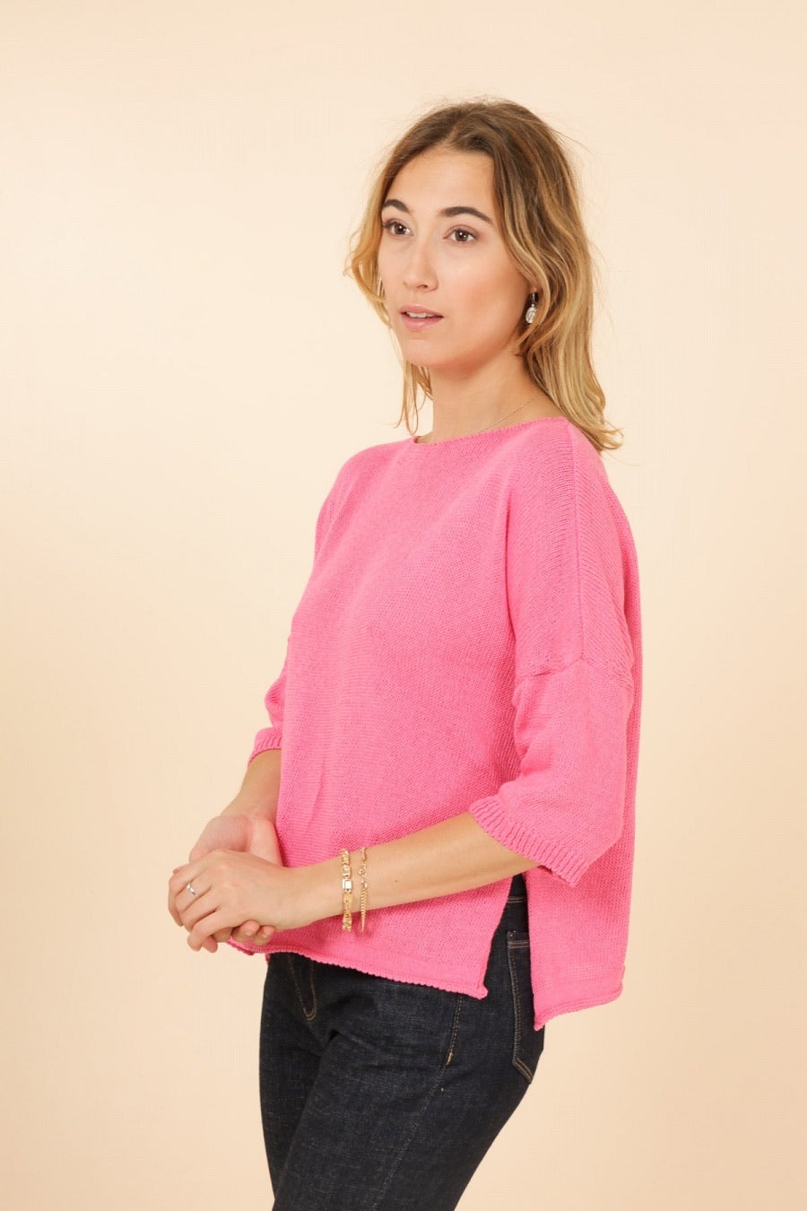Woman wearing a bright pink sweater against a beige background