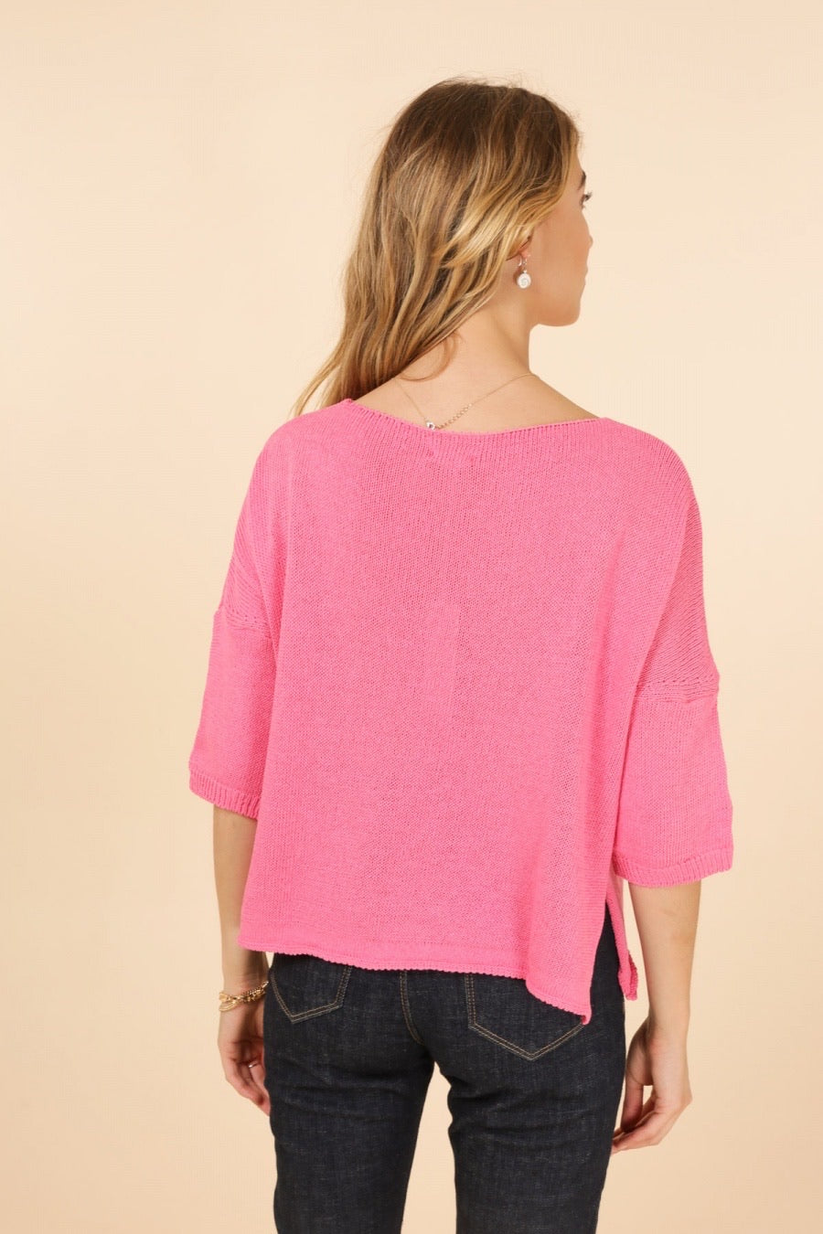 Woman wearing a pink sweater with a beige background