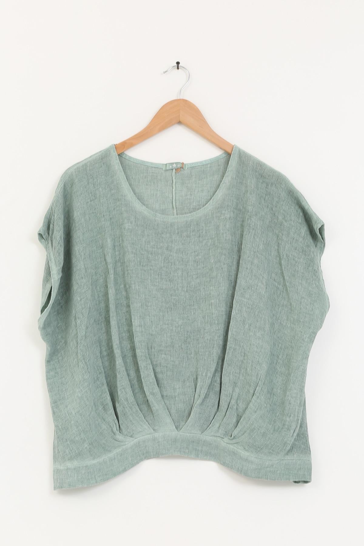 Green sleeveless top on a wooden hanger against a white background