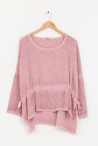 Pink sweater with a belt on a wooden hanger against a white background