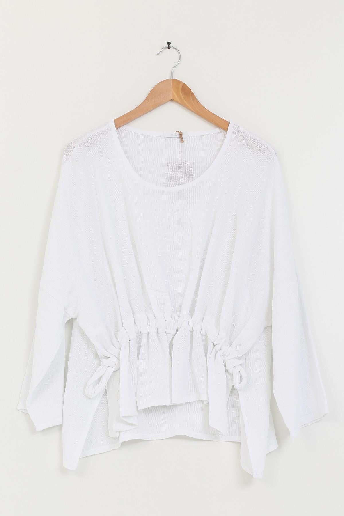 White blouse on a wooden hanger against a white background