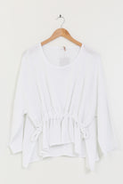 White blouse on a wooden hanger against a white background