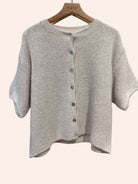 Beige knit cardigan on a hanger with 'nais' label.