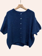 Blue cardigan on a hanger against a beige background