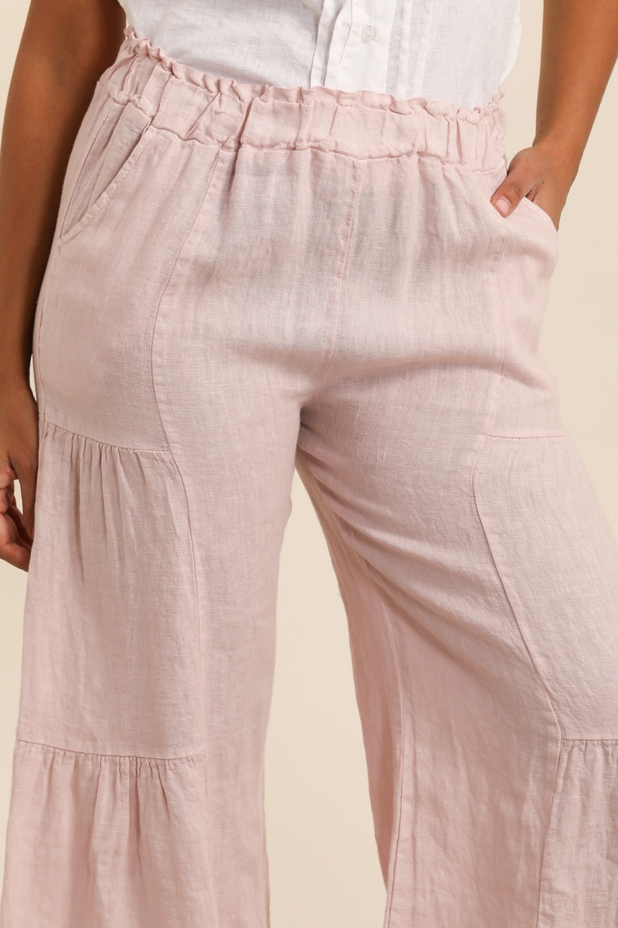 Pink tiered pants worn by a person on a beige background