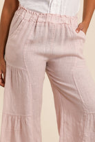 Pink tiered pants worn by a person on a beige background