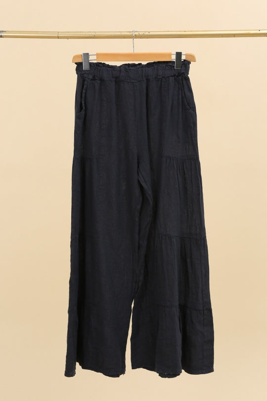 Navy wide-leg pants hanging on a beige background
