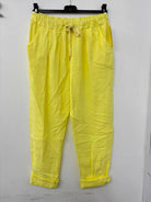 Yellow pants with a drawstring on a hanger against a white background