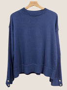 Blue sweater on a hanger against a white background