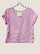 Pink cotton gauze top with buttons on a hanger against a white background